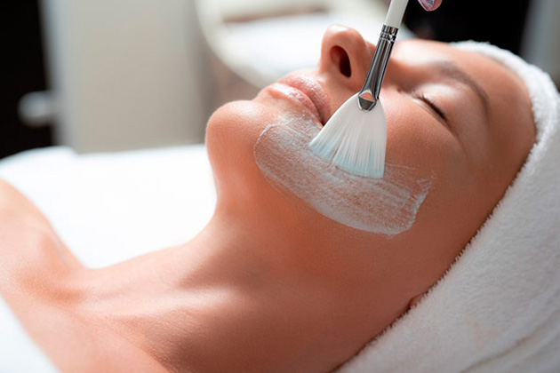 Creme sendo aplicado sobre o rosto de uma mulher branca durante o processo de revitalização facial